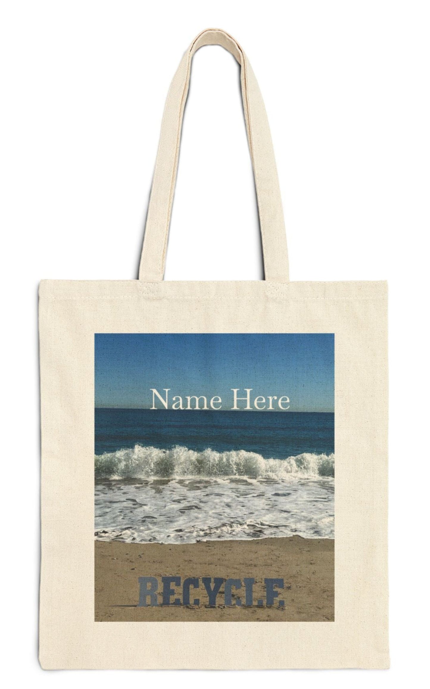 personalized recycle tote bag in natural color the recycle letters are on a sandy shore backed by waves from a blue sea with a blue sky backdrop.