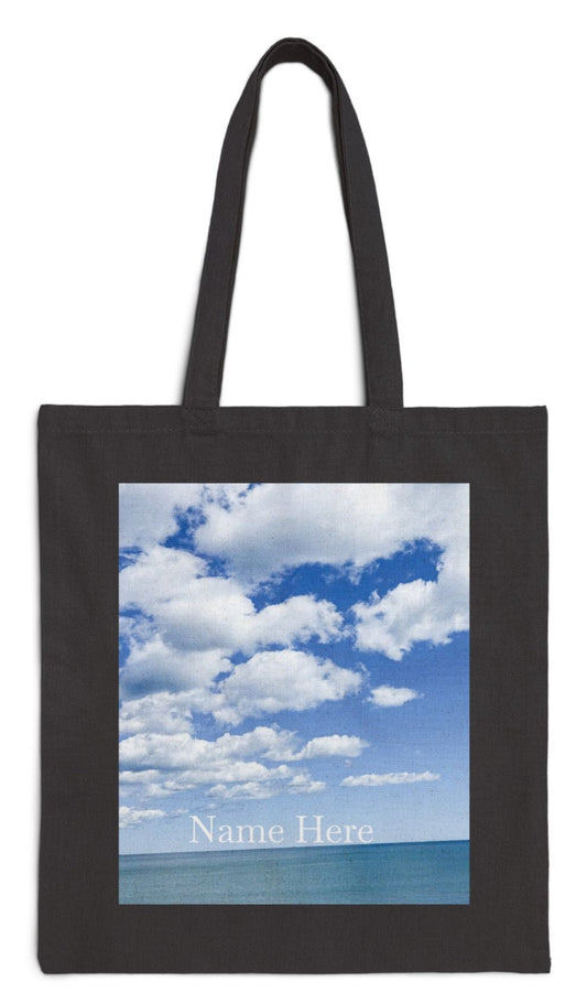 personalized everyday tote bag with bright blue sea and sky and puffy white clouds framed in black cotton canvas