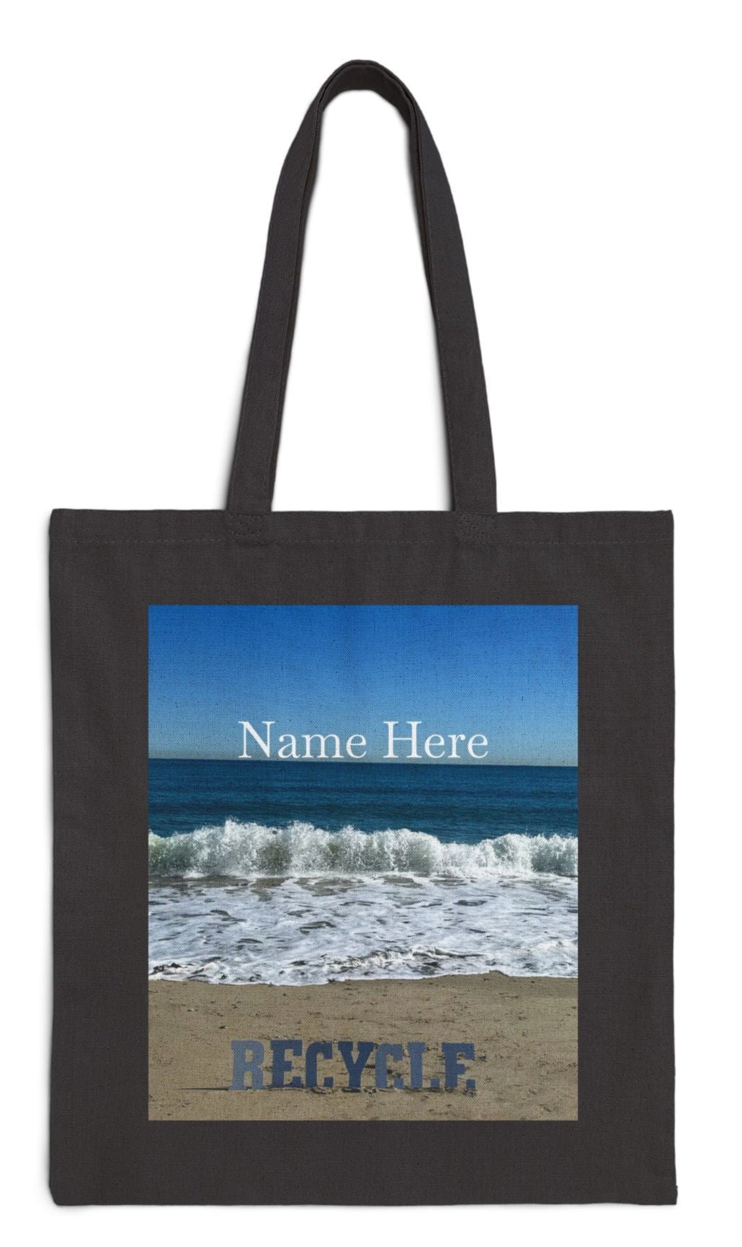 recycle tote bag in black the letters on a sandy beach with waves blue sea and sky